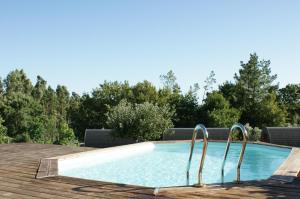 a swimming pool with two chairs next to a wooden deck at Casa Matilde - Alombada Family Lodge in Águeda