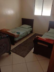 a bedroom with two twin beds and a window at Suite Apartment Fawzi in Agadir