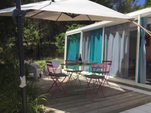 een patio met een tafel en stoelen en een parasol bij Gîte du Fenouil in Lézignan-Corbières