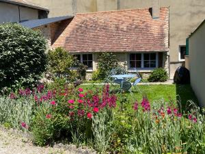 einen Garten mit rosa Blumen vor einem Haus in der Unterkunft Le Clos de la Tannerie in Saint-Aquilin-de-Pacy