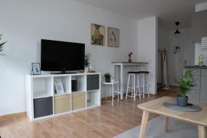 uma sala de estar com uma televisão de ecrã plano num armário branco em FULL HOUSE Studios - Southern Prime Apartment em Leipzig