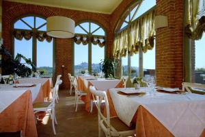 un restaurante con mesas y sillas blancas y ventanas en Villa Morneto en Vignale