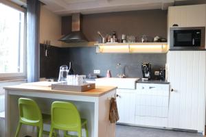 una cocina con sillas verdes en una barra de cocina en Apartmenthaus Hinterer en Bad Goisern