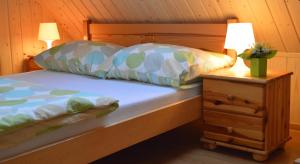 łóżko z 2 poduszkami i stół z lampką w obiekcie Pokoje Gościnne Arnika Górska w Szklarskiej Porębie