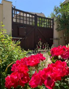 un montón de flores rojas delante de una puerta en Le Clos de la Tannerie, en Saint-Aquilin-de-Pacy