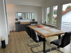 a dining room with a wooden table and black chairs at Traumhafter Bergblick im Allgäuer Luftkurort in Buchenberg