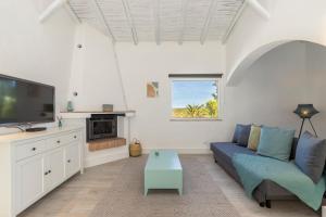 a living room with a blue couch and a tv at Palmeiras Cottages in Mexilhoeira Grande