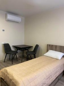 1 dormitorio con 1 cama, mesa y sillas en Prestige Apartments Berezinka, en Dnipro