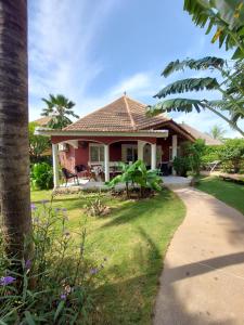 uma casa rosa com uma palmeira e um caminho em Villa Teranga em Saly Portudal