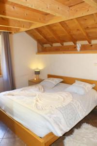 a large white bed in a room with wooden ceilings at Chalet Savoyard Balcon de Villy in Étaux