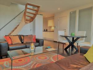 a living room with a couch and a table and a staircase at Cosy & charming holiday house in Damme in Damme