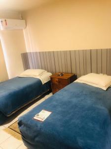 a hotel room with two beds and a night stand at Villa Apart Hotel in Lages