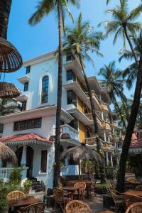 um hotel com cadeiras e palmeiras em frente em Sao Domingos em Cavelossim