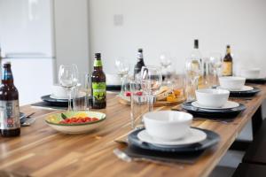 - une longue table en bois avec des bouteilles de vin et des verres dans l'établissement Rumney House, à Cardiff