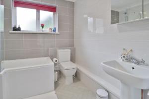 a white bathroom with a toilet and a sink at Rumney House in Cardiff