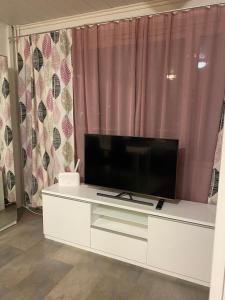 ein Wohnzimmer mit einem großen TV auf einem weißen Schrank in der Unterkunft Polaris Homes for You in Rovaniemi