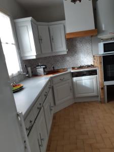 una cocina blanca con armarios blancos y fregadero en En Beauvoir, en Cormot-le-Grand