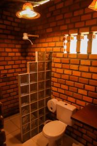 a bathroom with a toilet and a brick wall at Palma Adventure Hostel in Barreirinhas