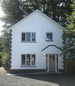 una casa blanca con una puerta y una valla en Haul y Bore en Aberystwyth