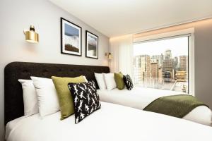 two beds in a hotel room with a window at Wilde Aparthotels London Aldgate Tower Bridge in London +33 photos