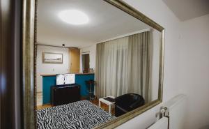 a mirror reflecting a bedroom with a bed and a desk at Prestige apartment in Gornji Milanovac