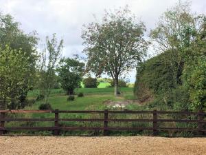 a wooden fence in front of a field with trees at Contemporary Cottage outside South Harting in South Harting
