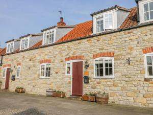 an old brick building with a red door at Barn Cottage in York