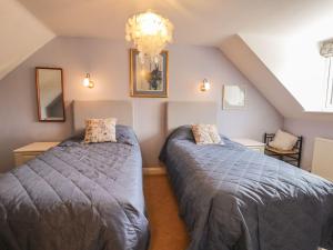 a attic bedroom with two beds and a chandelier at Barn Cottage in York
