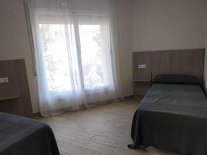 a bedroom with two beds and a large window at Apartamento Estels in L'Ampolla