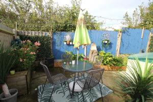 um pátio com uma mesa, cadeiras e um guarda-sol em Peaceful Garden Apartment em Herne Bay
