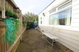 un banco sentado fuera de una casa al lado de una valla en Peaceful Garden Apartment en Herne Bay