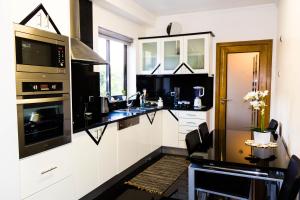 een keuken met zwart-witte werkbladen en een magnetron bij Apartamento Batista by Horizon View Madeira in Funchal