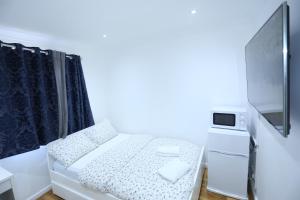 Habitación blanca pequeña con cama y TV en Cosy Room with en-suite bathroom and shared kitchen en Thamesmead