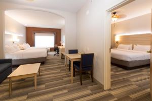 a hotel room with two beds and a couch at Holiday Inn Express Hotel & Suites Grand Blanc by IHG in Grand Blanc