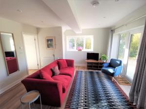 a living room with a red couch and a blue chair at Contemporary Cottage outside South Harting in South Harting