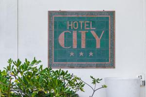 ミラノ・マリッティマにあるHotel Cityのホテルの街の壁掛けを読む看板