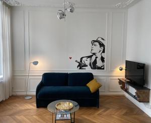 a living room with a blue couch and a tv at La Cour in Nancy
