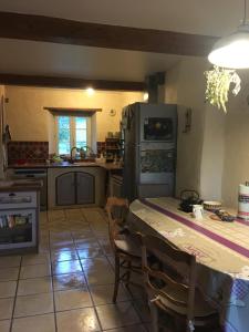 eine Küche mit einem Tisch mit Stühlen und einem Kühlschrank in der Unterkunft Prieuré St Jean à Autichamp in Autichamp