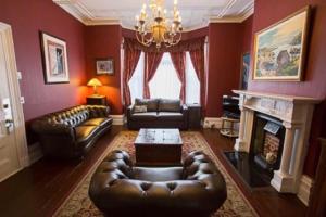sala de estar con muebles de cuero y chimenea en The Roses Heritage Inn, en St. John's