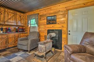 a living room with two chairs and a wood stove at Wright City Cabin with Fire Pit and Forest Views! in Wright City