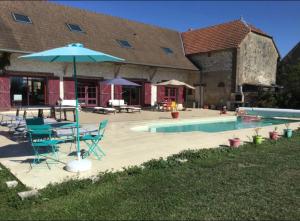 TurnyLE GITE DE VERONIQUE,jo 2024的一个带桌子和遮阳伞的庭院,毗邻一个游泳池
