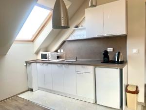 une cuisine avec des armoires blanches et un évier dans l'établissement ,,Адела”-апартамент за гости, à Velingrad