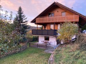 duży drewniany dom z balkonem na wzgórzu w obiekcie Ferienwohnung (idyllische Lage + 1800m² Garten) w mieście Niederstetten