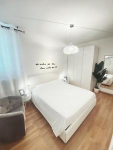 a white bedroom with a large bed and a chair at Chic In The City in Bolzano