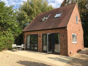 ein Haus mit Glastüren und einem Tisch auf der Terrasse in der Unterkunft Contemporary Cottage outside South Harting in South Harting