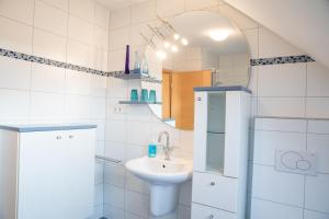 a white bathroom with a sink and a mirror at Ferienwohnung Ella in Meckenbeuren +23 photos