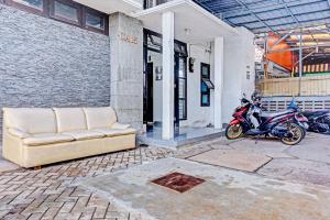een bank en een motorfiets geparkeerd voor een gebouw bij SUPER OYO 90689 Lily House in Tangerang