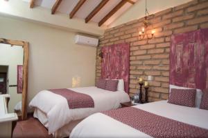 a bedroom with two beds and a brick wall at Casa 1800 Suchitoto Boutique in Suchitoto