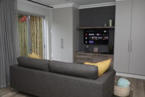 a living room with a gray couch and a yellow pillow at Sunbird Bliss Luxury Self-catering Apartment in Wilderness