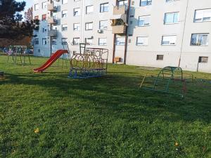 a playground with a slide in the grass in front of a building at Apartment Close2park *** in Čakovec